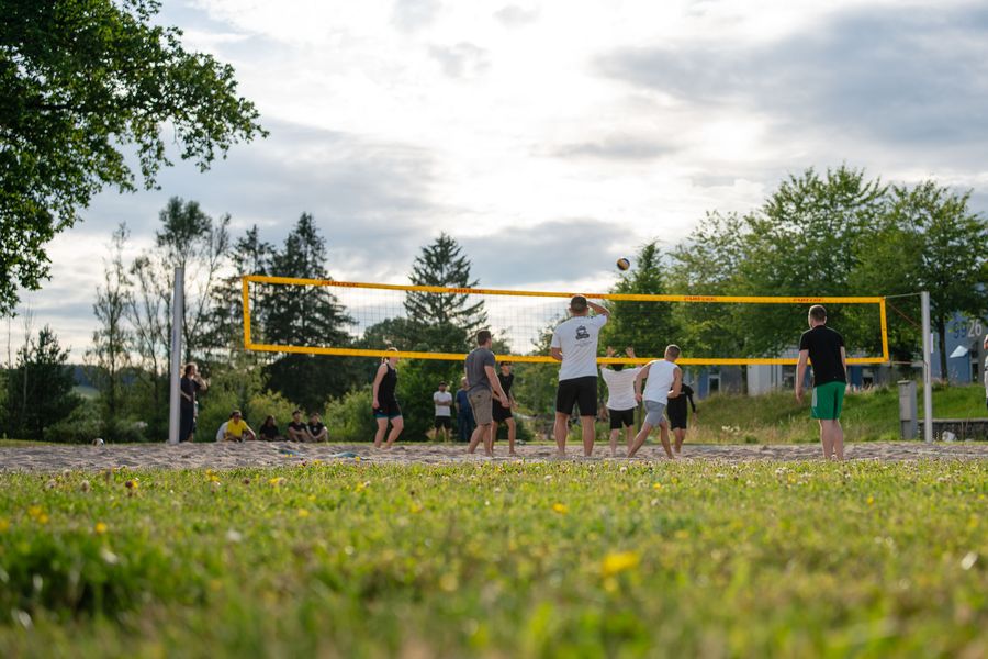 Studierende spielen Beachvolleyball auf dem Sandplatz am Campus.